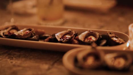 a hand delicately picks oysters from a platter in a warmly lit environment, creating an intimate and cozy atmosphere