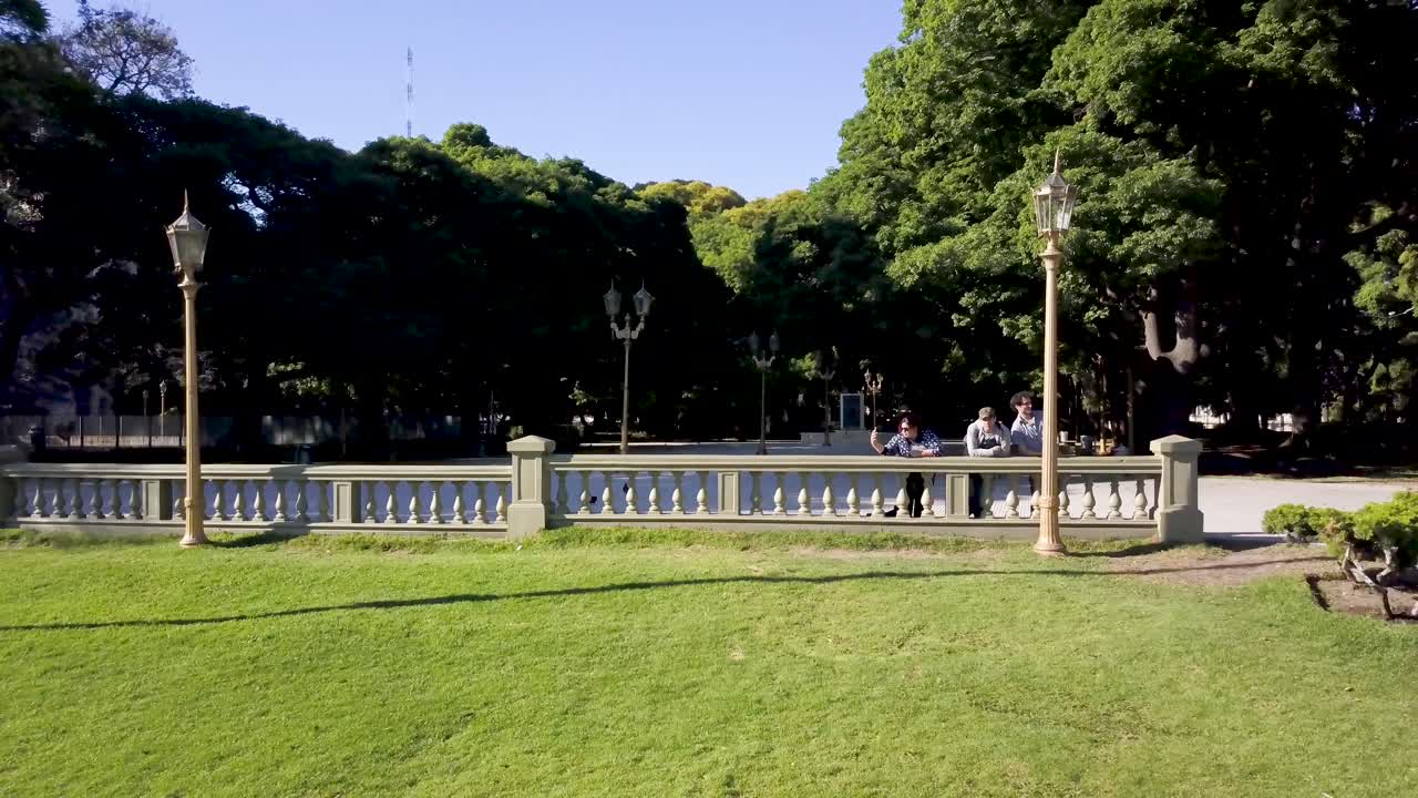 Aerial shot of people relaxing in Plaza San Martin surrounded by vegetation, Buenos Aires. DOLLY OUT