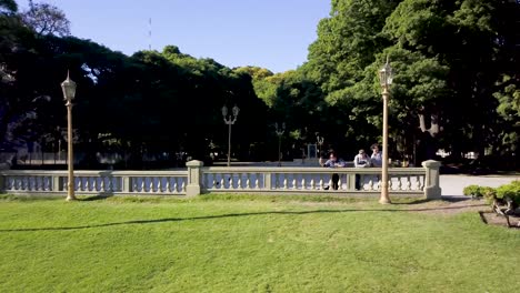 aerial shot of people relaxing in plaza san martin surrounded by vegetation, buenos aires. dolly out