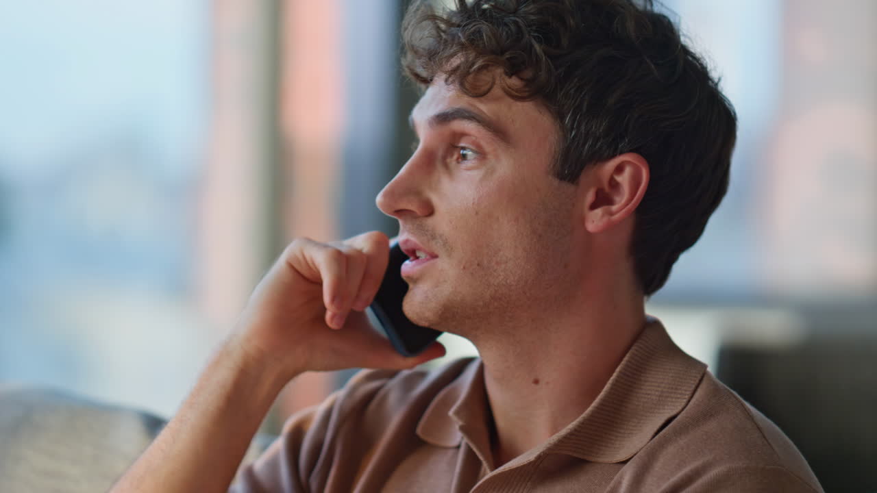 Home man talking cellphone relaxing on comfortable apartment sofa closeup