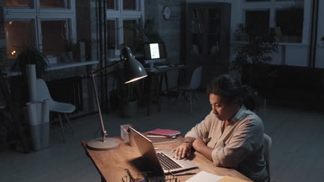 woman working on laptop at night in a home office