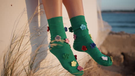 happy girl feet dangle in colorful stylish socks closeup. carefree kid at shore