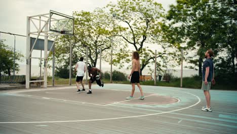 Ein-Mann-In-Einem-Grauen-T-Shirt-Serviert-Einen-Basketball,-Der-Von-Seinem-Teamkollegen,-Einem-Mann-Mit-Schwarzer-Hautfarbe,-Entgegengenommen-Wird,-Der-Ein-Fantastisches-Tor-Schießt