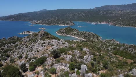 tour aéreo sobre la antigua ciudad de aperlai con montañas, aguas azules y barcos que navegan en turquía