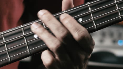 el músico toca el bajo en su propio estudio, cerca de la mano en el cuello