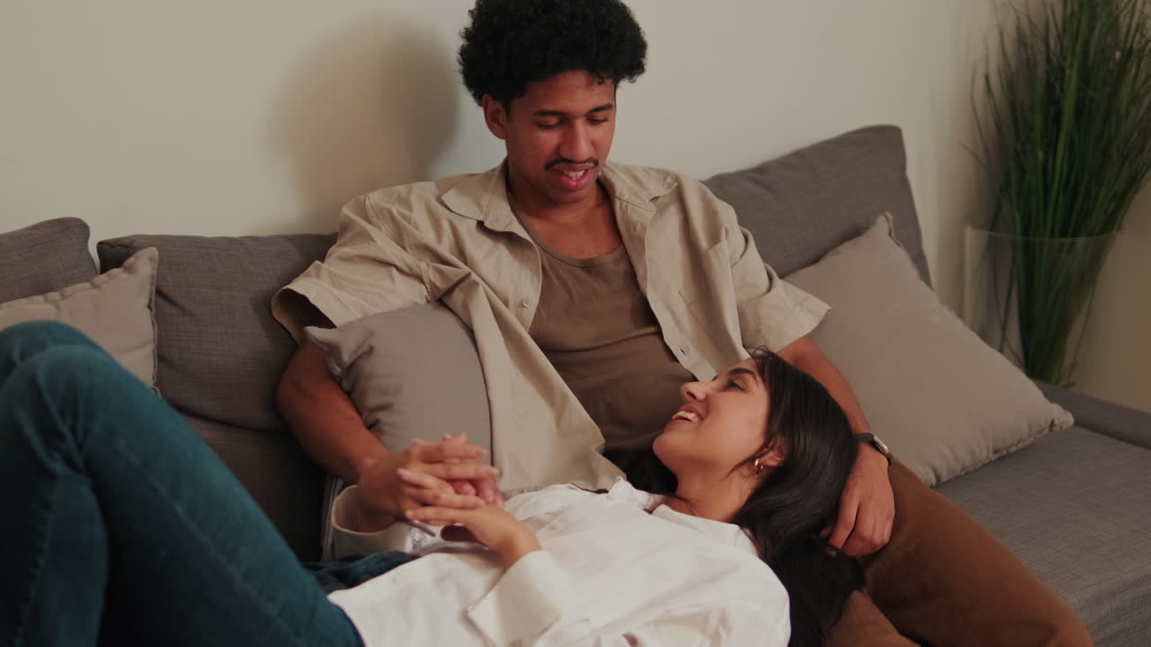 Happy Young Couple Relaxing and Talking on Sofa at Home