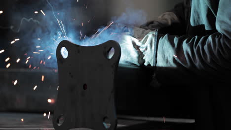 worker welding metal plate to steel tubular pipe in an industrial factory - close up, slider shot