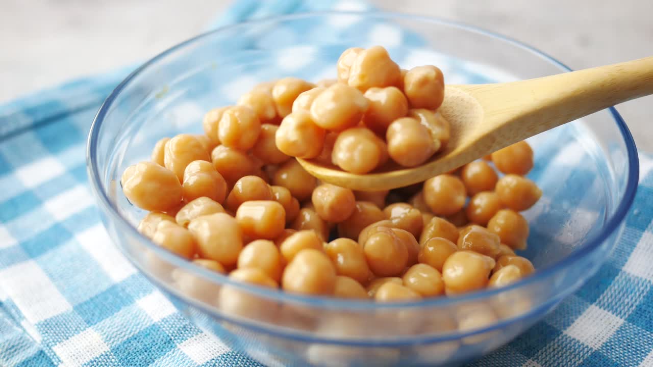 Close up of chickpeas in a bowl with a wooden spoon
