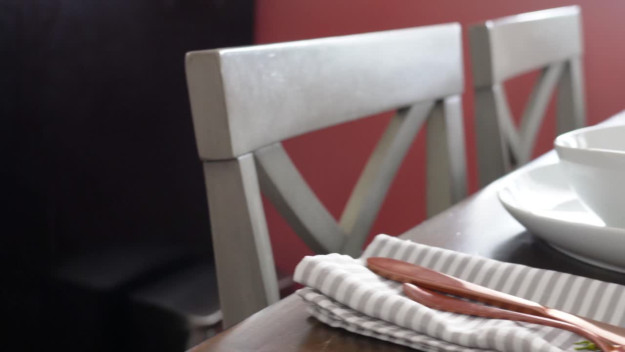 Classy Restauraunt Table Set for Dinner with White Plates and Gold Silverwhere with Beautiful Flowers and Lit Candels next to Sunny Window, Gimbal Pan Right Movement, Forks, Knives and Napkins