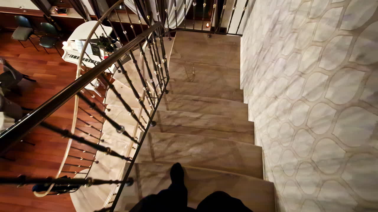 First-person slow motion view of walking down stairs in a restaurant, looking downward.