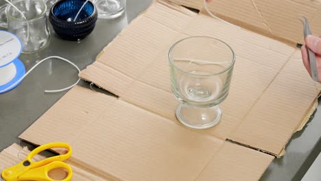 gluing candle wicks to the bottom of a jar to make candles