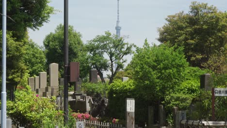 Handheld-Kippen-Von-Gedenkgrabsteinen-Auf-Dem-Yanaka-Friedhof-Im-Vordergrund-Mit-Dem-Tokyo-Skytree-Tower-Im-Hintergrund,-Tokio,-Japan-An-Einem-Sonnigen-Tag