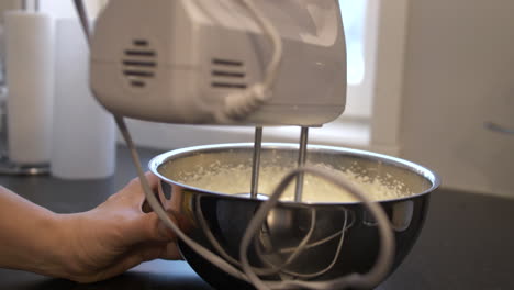 close-up of person making whipped cream with electric hand mixer