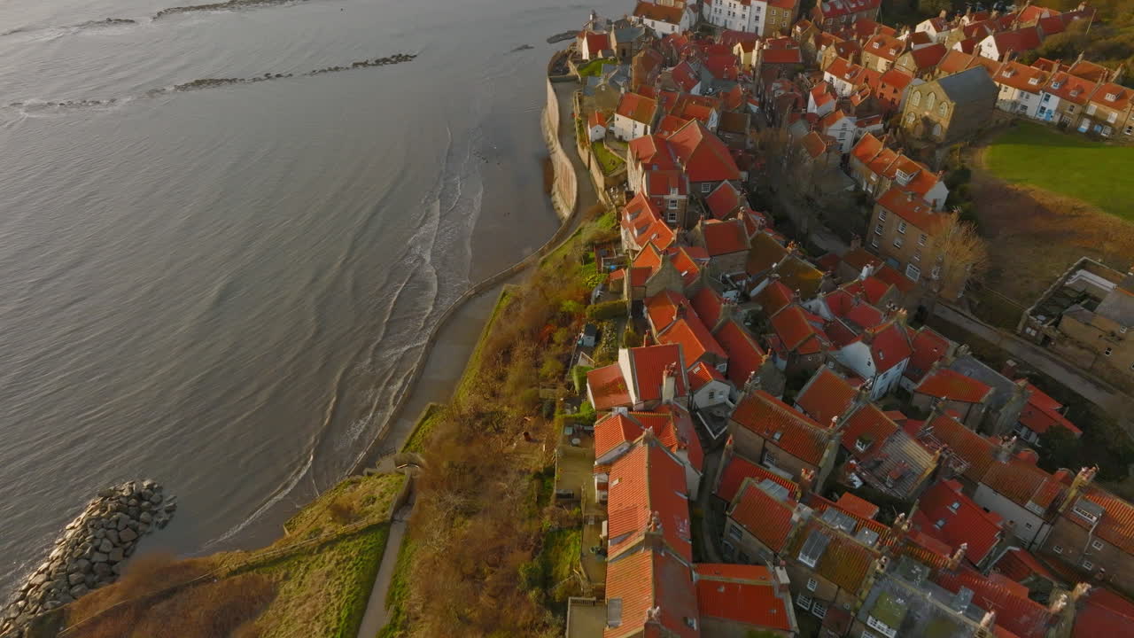 Costa Patrimonial de North York Moors, Baía de Robin Hood. Voo de drone aéreo sobre a vila de RHB ao amanhecer, com afastamento da rampa de acesso e panorâmica ascendente. DJI Mavic 3 Cine ProRes 422, Março de 2022, Clipe 2.