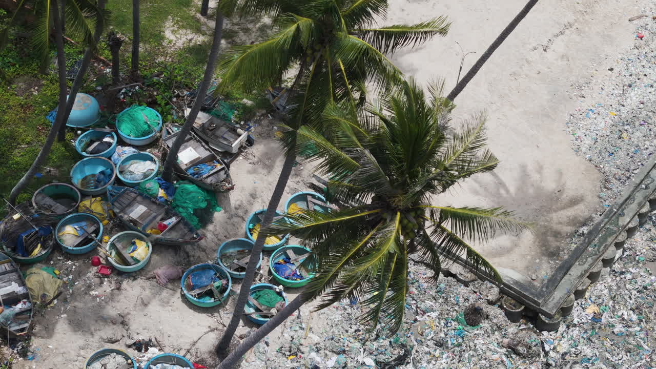 Tropical beach with palms covered in rubbish, aerial top down view