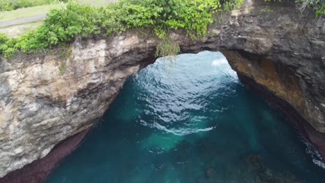 waves of turquoise clear water break through natural arch bridge of broken beach on nusa penida island