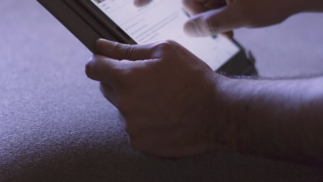 Shooted in slow motion showing man's hands browsing social media or playing with a mobile tablet at evening