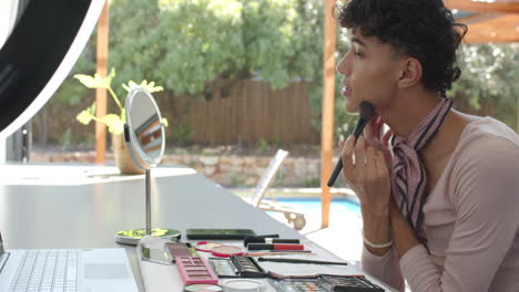 applying makeup, non binary person using brush and mirror at home vanity