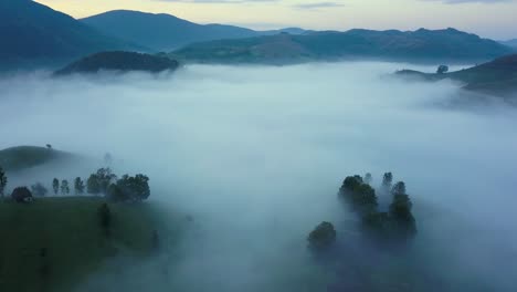 aerial footage taken before sunsrise in the countryside of transylvania while flying above a valley covered in fog