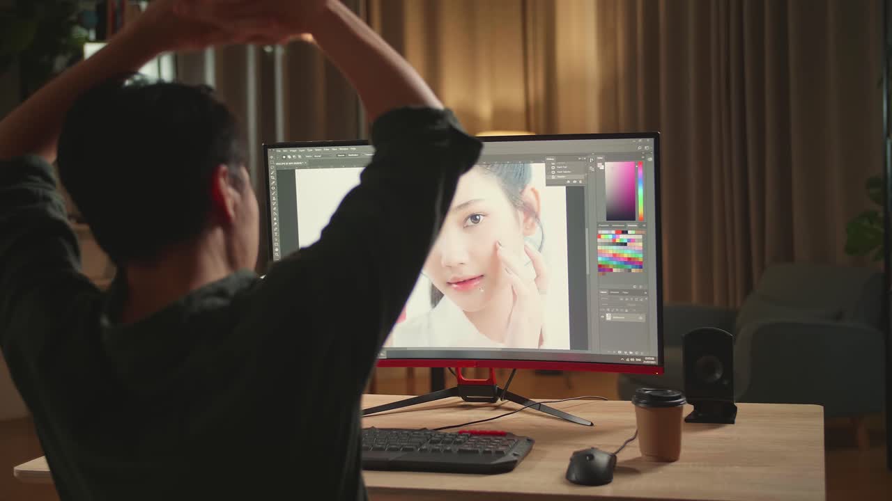 Asian Male Digital Editor Stretching While Works In Photo Editing Software On His Personal Computer With Big Display, He Works At Night