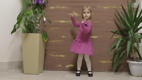 pequeño niño baila cerca de macetas y valla de madera. sentirse feliz, sonriendo