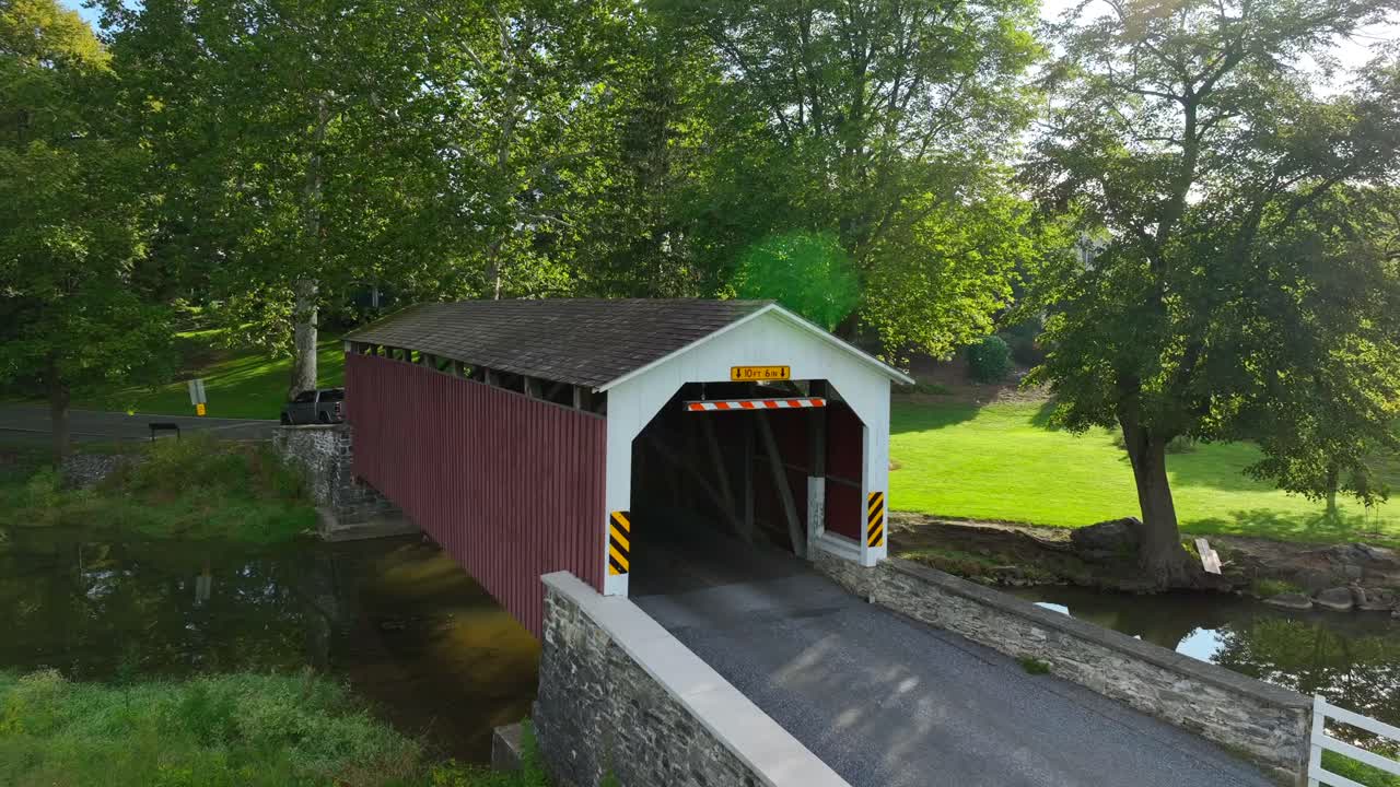 Truck driving through covered bridge over creek in rural USA