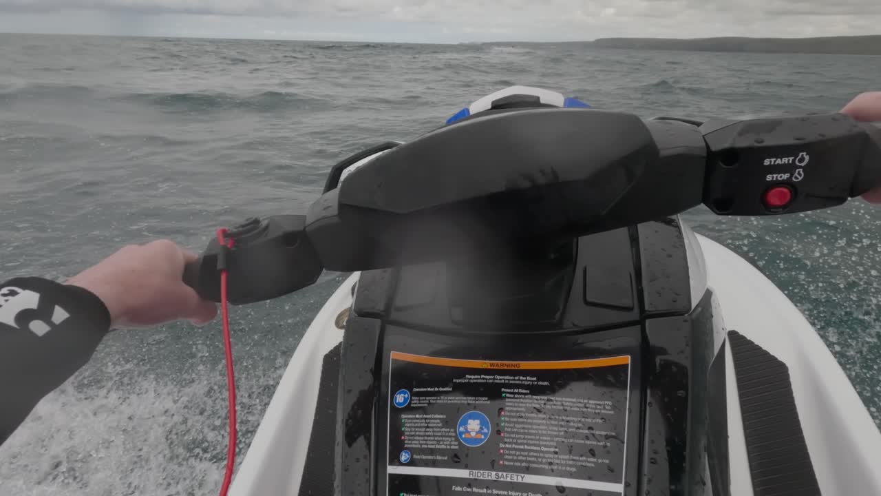 Rekaman POV seorang pria yang mengendarai jet ski melintasi laut berombak di Newquay, Cornwall.