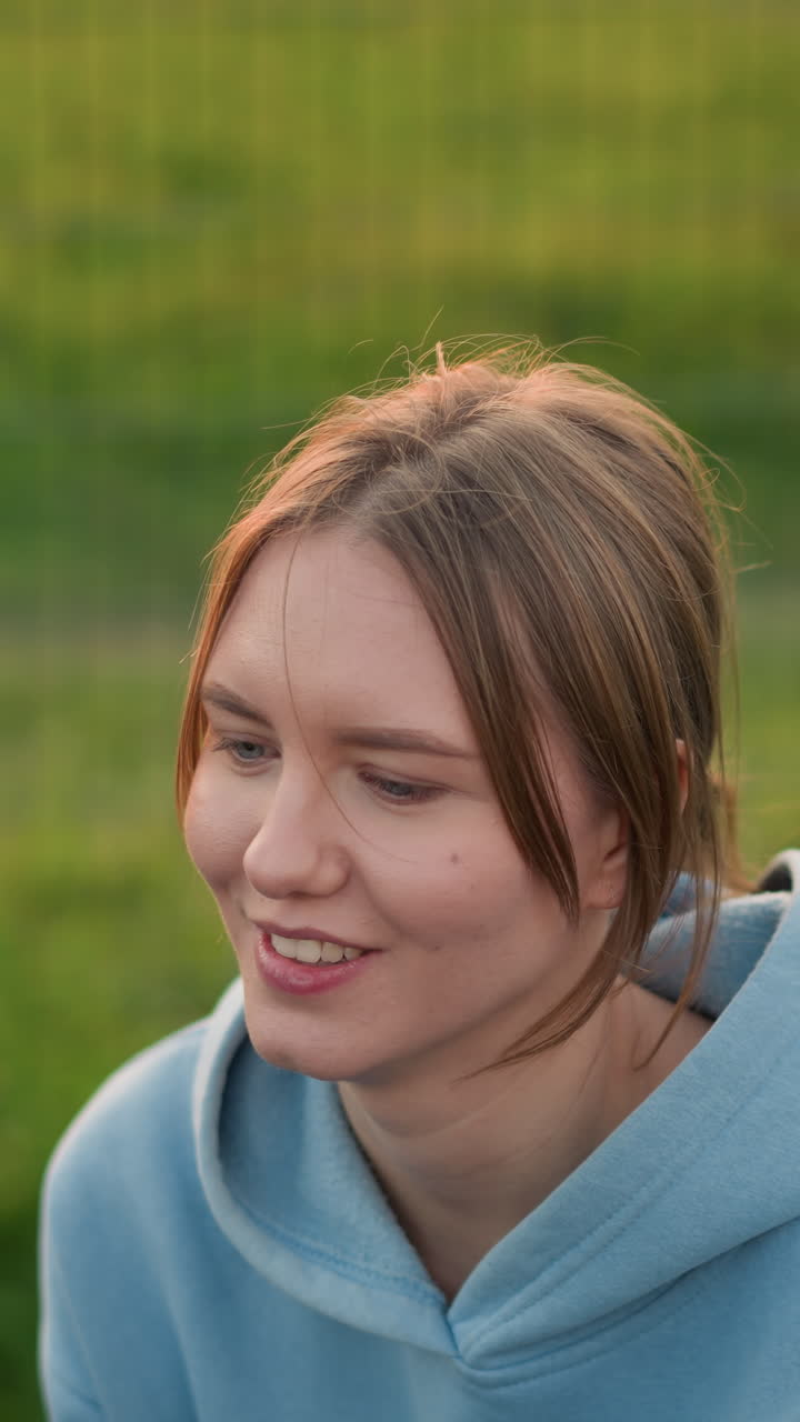 primer plano de una mujer con el cabello atado hacia atrás jugando al voleibol, centrándose en la sesión de entrenamiento, intenta atrapar la pelota mientras vuela, con un campo abierto y una valla de barra en el fondo detrás de ella