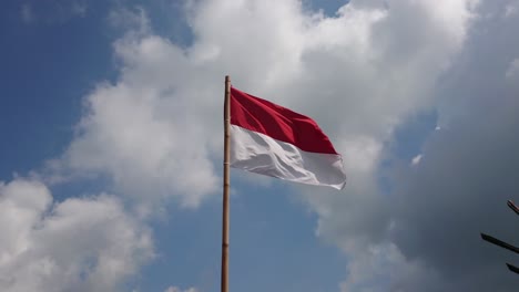 indonesian flag waving in blue sky clouds background