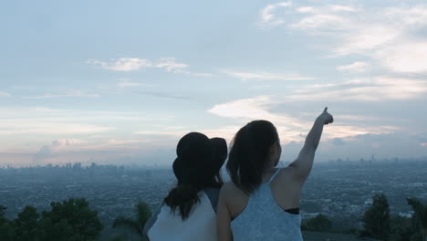 two teenage girls taking a photo and admiring the scenery of a city sunset