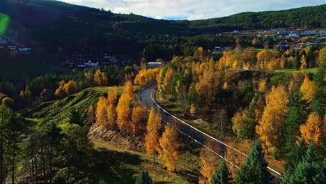 bird's-eye-view-over-the-mountains-in-norway-with-a-road-winding-through-the-green-forests