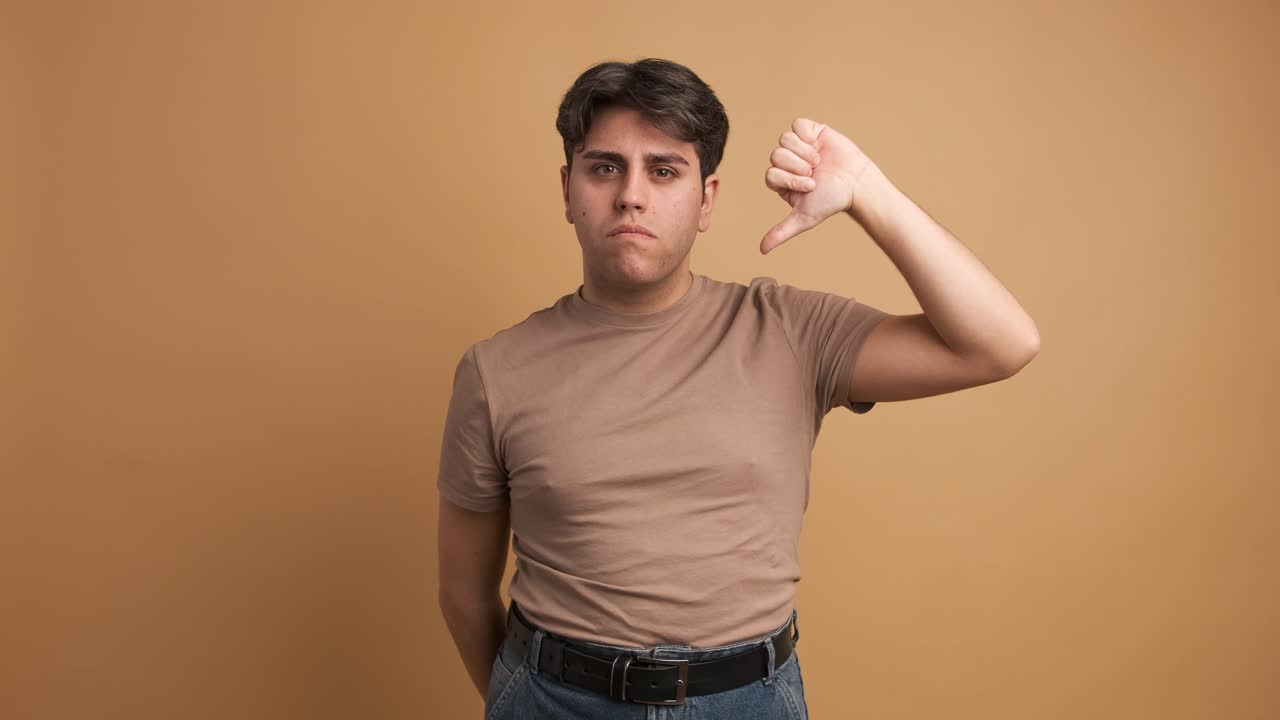Young man gesturing disagreement with thumb down