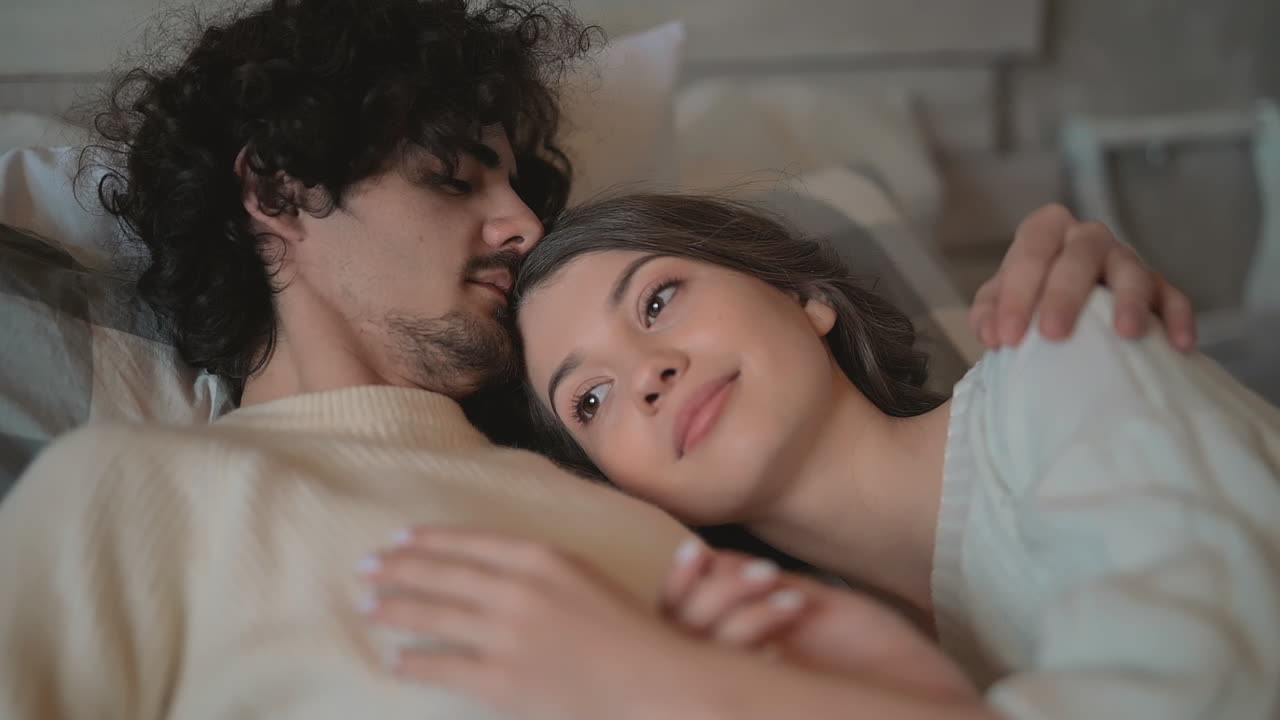 close up of young romantic cute couple lying in bed wearing winter clothes