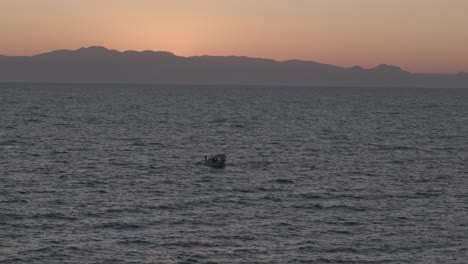 Luftaufnahme-über-Einem-Segelboot,-Das-Durch-Das-Malerische-Mittelmeer-Vor-Dem-Leuchtend-Orangefarbenen-Sonnenuntergangshimmel-Navigiert