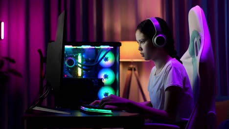 una adolescente asiática seria jugando videojuegos en la computadora