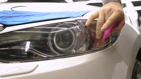 man covering car with vinyl polyurethane tape. films for the car. sticker protective film on the headlight of the car