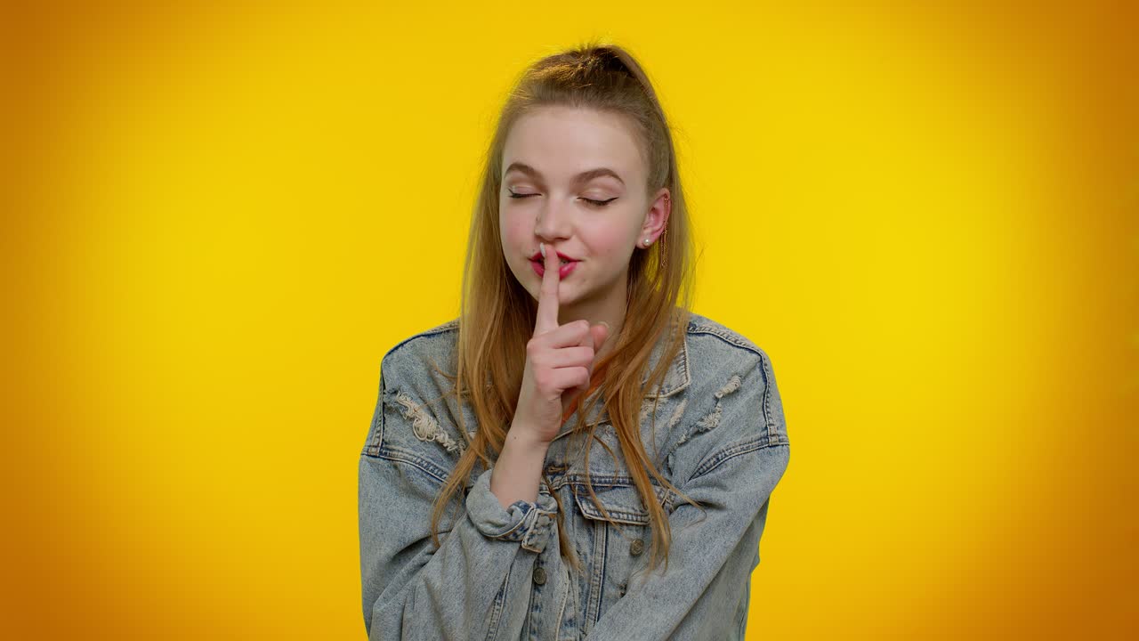 Ragazza fa un gesto di silenzio portando l'indice alle labbra, shhh