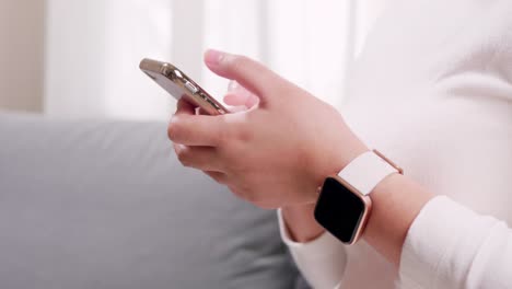 Close-up-of-hand-woman-using-smartphone-and-smartwatch-in-the-living-room-for-business-and-shopping-internet-and-texting-communication