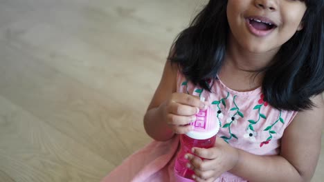 niña pequeña bebiendo de una botella de agua rosa