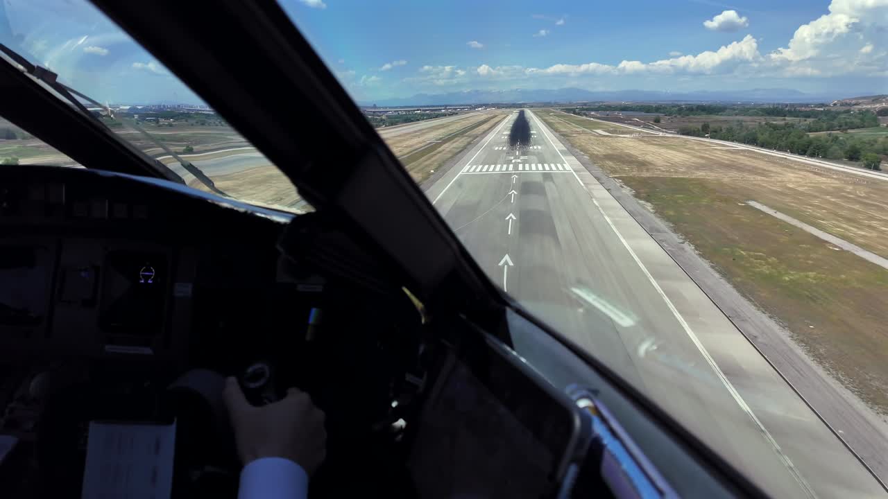 Mano di un copilota caucasico ai comandi di un aereo a reazione in un avvicinamento finale e atterraggio in tempo reale all'aeroporto di Madrid in una giornata soleggiata e ventosa, con poche nuvole in un cielo blu.