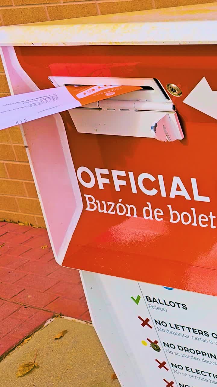 Vertical footage captures a hand inserting a mail-in ballot envelope into an official ballot box, highlighting civic duty, trust, democracy, safety, freedom, responsibility, and secure elections