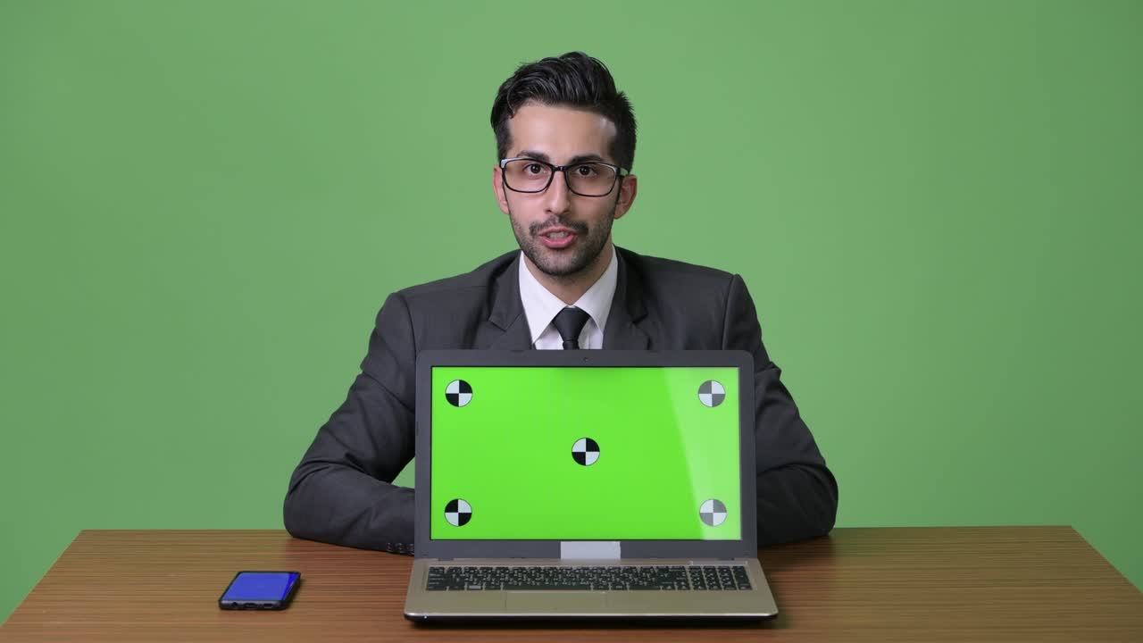 joven empresario persa barbudo y guapo contra un fondo verde