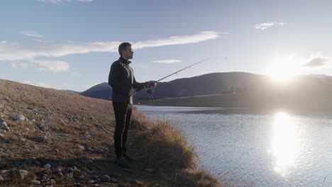 young, lonesome fisherman casting out rod at golden hour