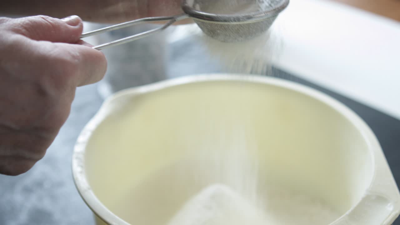 las manos de la mujer tamizan la harina.