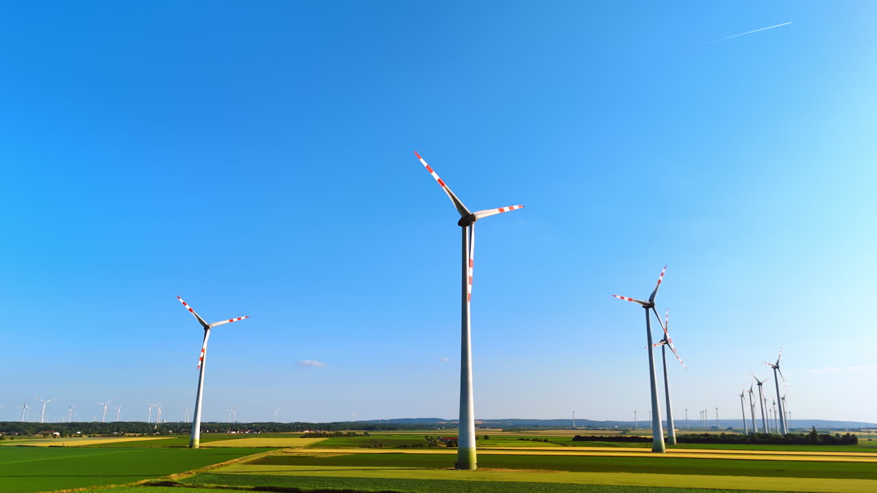 Sunny Europe with wind turbines. Wind turbines dot the landscape under a clear blue sky in Europe, surrounded by lush green fields and farmland