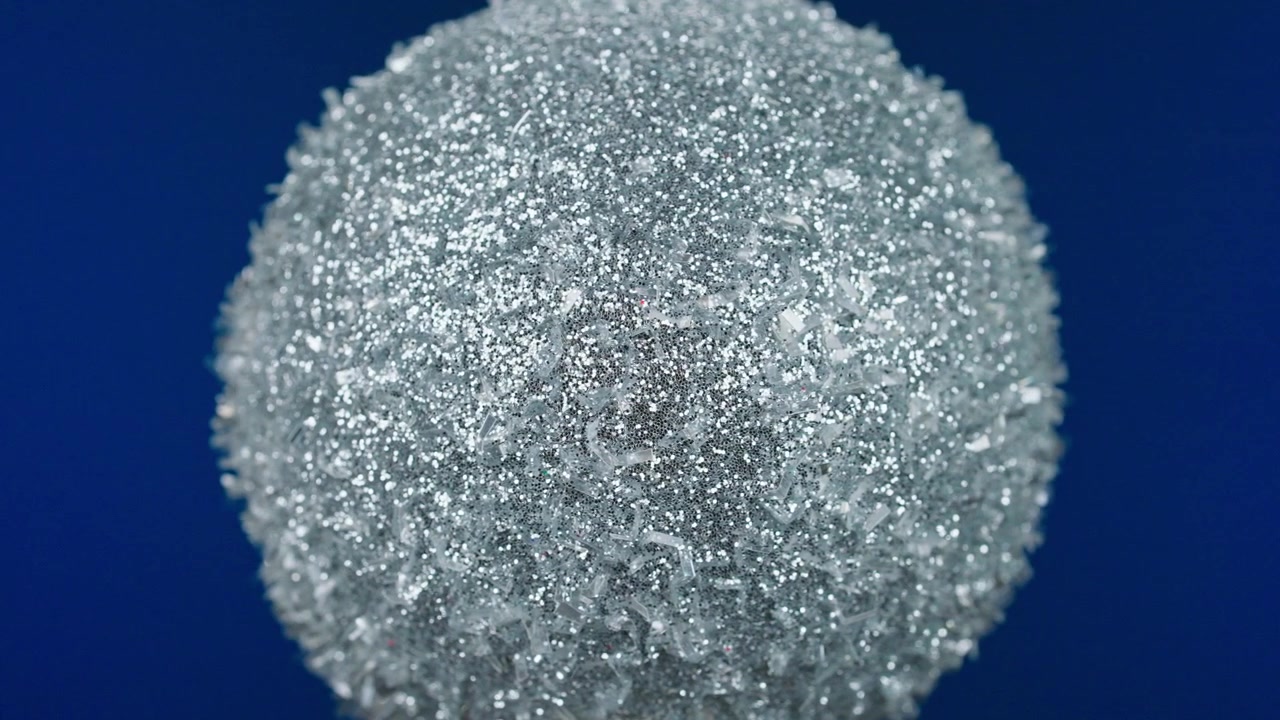 Närbild på en gnistrande silverglitterboll på blå bakgrund