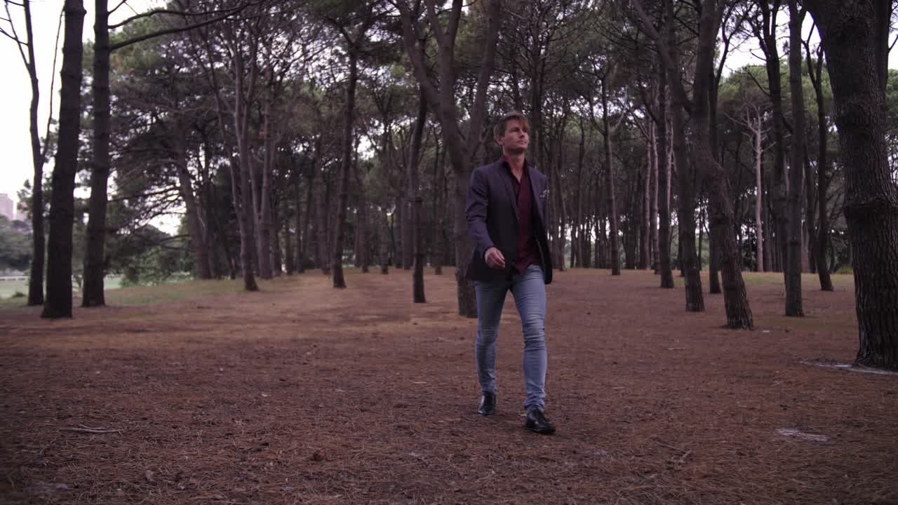 Full shot of man walking in pine forest dressed up