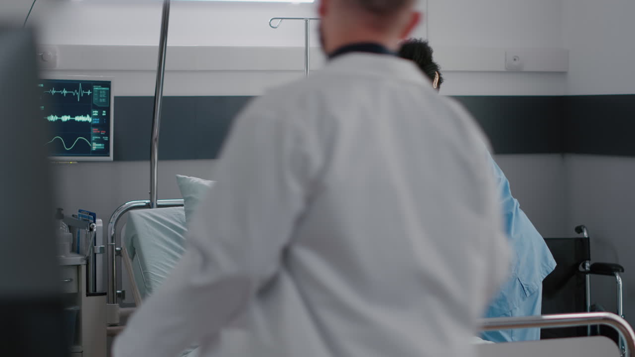 enfermera afroamericana ayudando al paciente a sentarse cómodamente en la sala del hospital