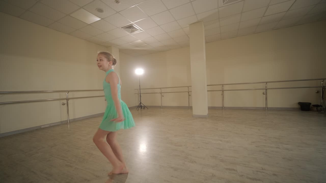 검은색 댄스웨어를 입은 젊은 발레 학생들이 나무 바닥과 벽에 장착된 바를 가진 넓은 발레 스튜디오에서 자세를 연습하는 그룹.