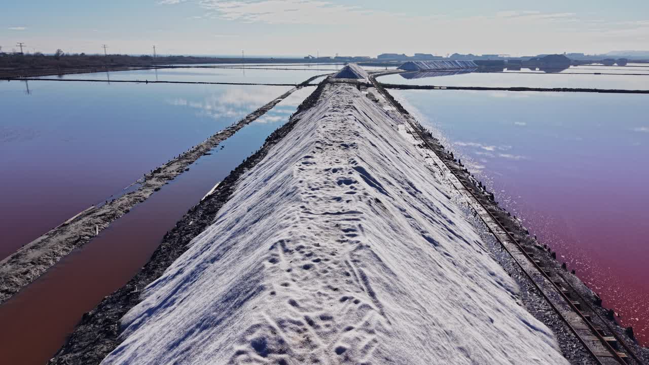 Salt mounds in fields near water bodies during bright daylight hours
